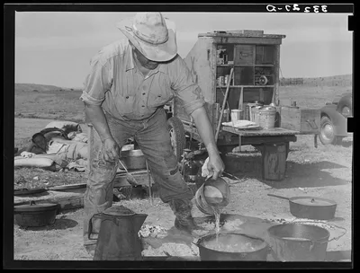 Camp cook at work with chuckwagon in background. Cattle ranch near…, 1939
