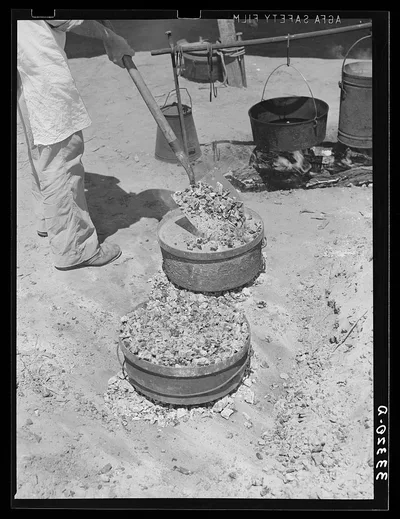 Piling coals on top of Dutch oven to bake bread. Ranch near Spur,…, 1939
