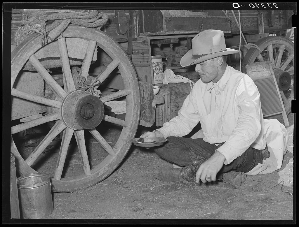 Cowboy eating dinner by the chuck wagon on SMS Ranch near Spur, 1939