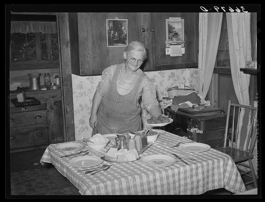 Mrs. George Hutton putting the food on the table for dinner. Pie…, New Mexico, 1940
