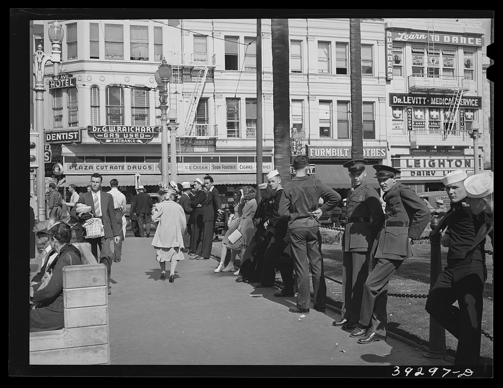 Sailors lined up against chain-rail in square in midtown. San Diego,…, California, 1941