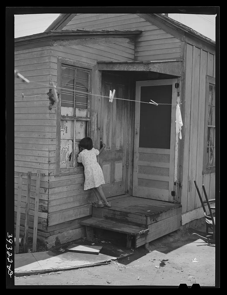 Little Mexican girl looking in window of her home. San Diego,…, California, 1941